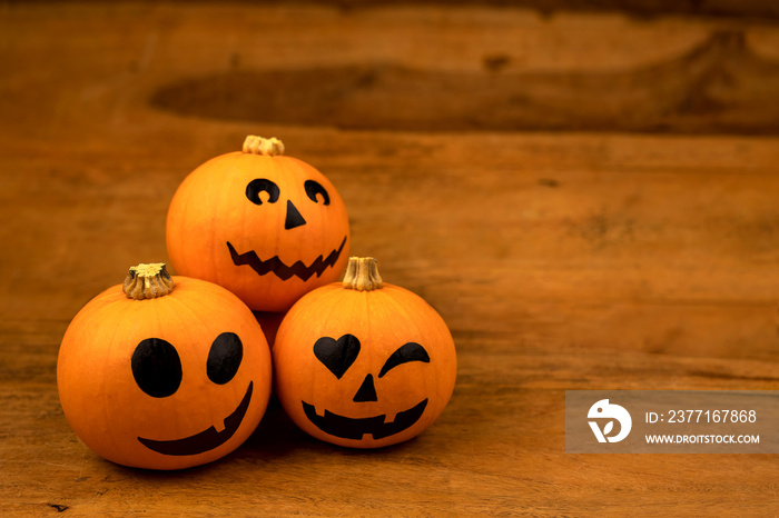 Little pumpkins with painted faces for Halloween on wooden background