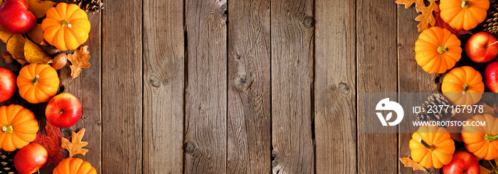 Autumn double border with pumpkins, leaves and apples. Above view on a rustic dark wood background w