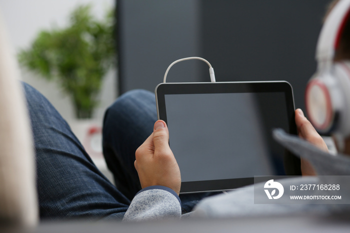 Male hand holds tablet in home setting while