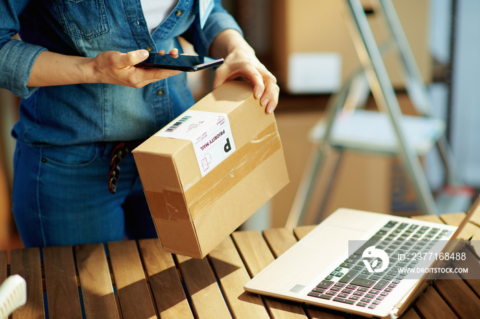 Modern female in jeans using smartphone app in warehouse