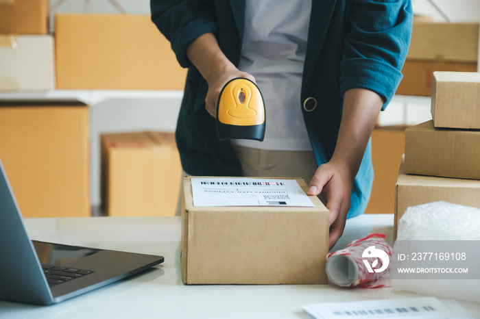 Young entrepreneur scanning online order box.