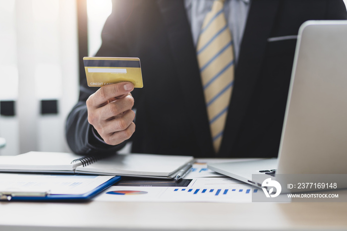 Businessman holding credit card using laptop and checking credit card limit for financial planning a