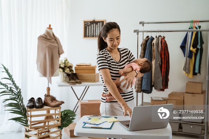 portrait of woman with baby working from home of her online ecommerce shop