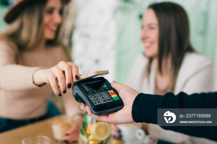 woman paying contactless with her smartphone in cafeteria