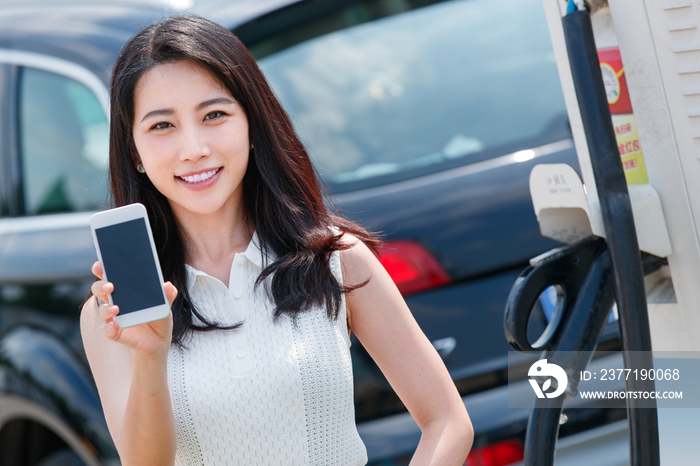 青年女人使用手机自助充电汽车