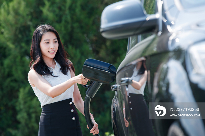 青年女人给汽车充电