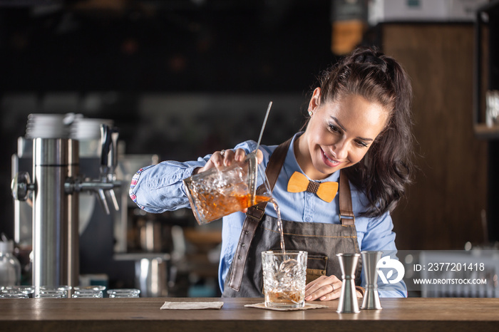 在酒吧里，漂亮的女服务员将老式鸡尾酒倒入装饰杯