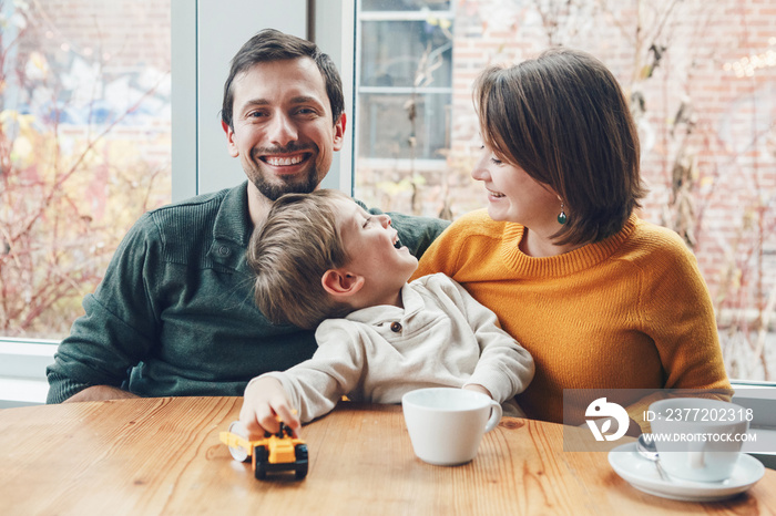 Portrait of white Caucasian happy family of three mother, father and son, sitting in restaurant cafe