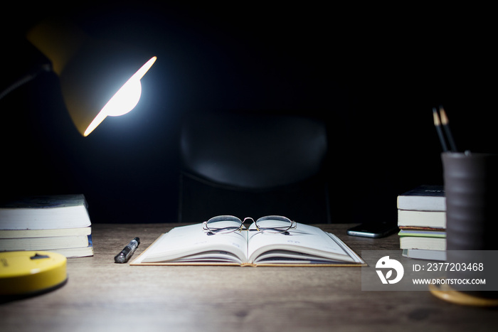 Reading table at night, Open books and glasses placed, Book Division and lighting lamps, Close-up on