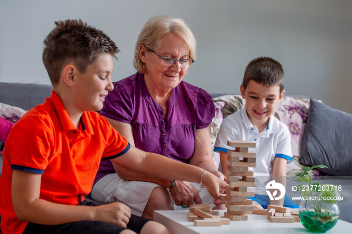 Two boys with grandmother playing game at home, Happy kids playing with senior woman at home. Family