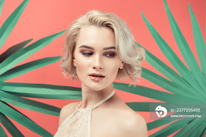 portrait of blonde woman in lace bra, isolated on red with palm leaves