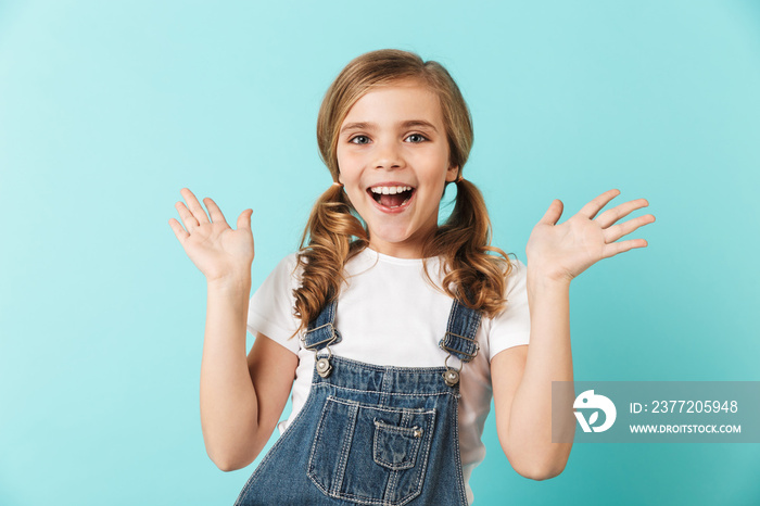 Pretty young little girl posing isolated over blue wall background.