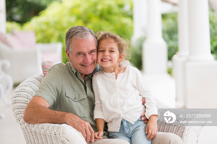 Portrait happy grandfather and granddaughter on patio