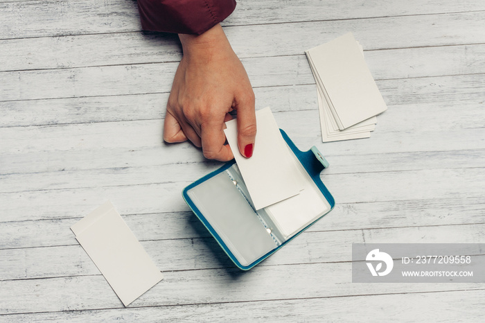 business card holder on a wooden table with white paper and a womans hand