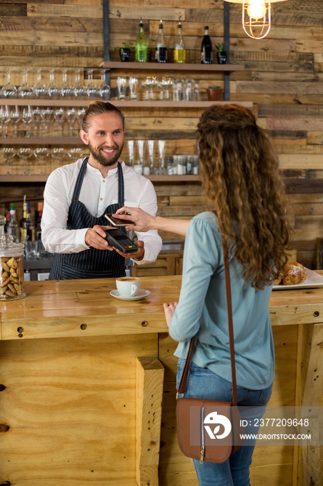 Woman paying bill through smartphone using NFC technology