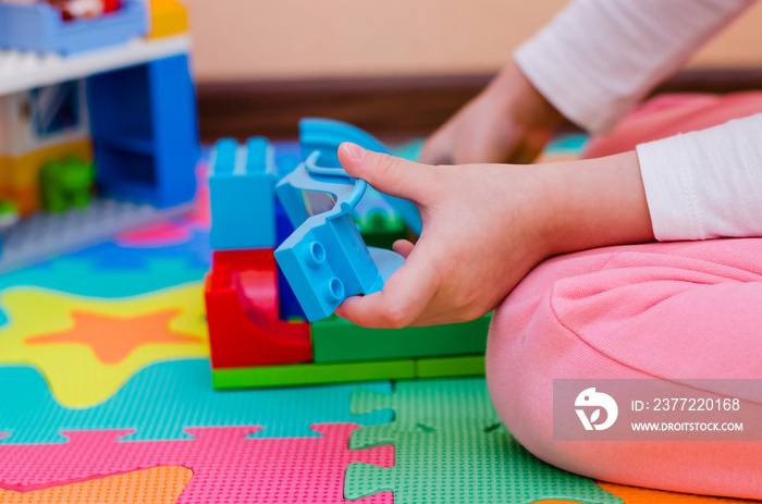 childs hands playing with colorful plastic bricks. Close up. Developing toys