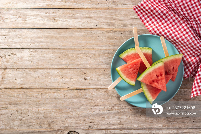 Watermelon slices popsicles on blue plate on rustic wooden table. Top view. Copy space