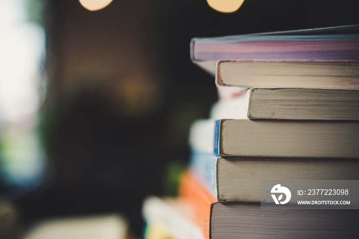 piles of books on table over blurred library background.