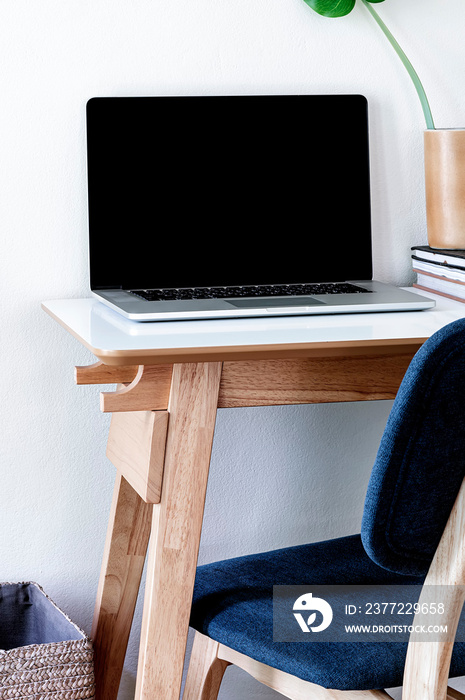 Mockup laptop with blank screen on wooden table in contemporary room, copy space, vertical view.