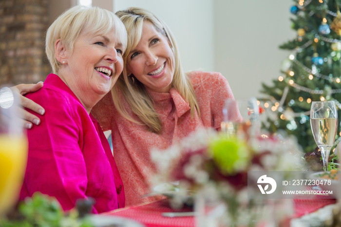 Mother and daughter hugging at Christmas dinner table