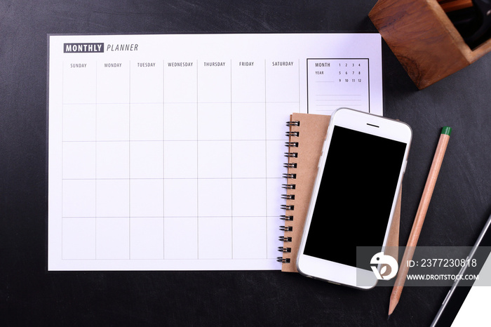 blank screen smartphone with notebook and planner schedule