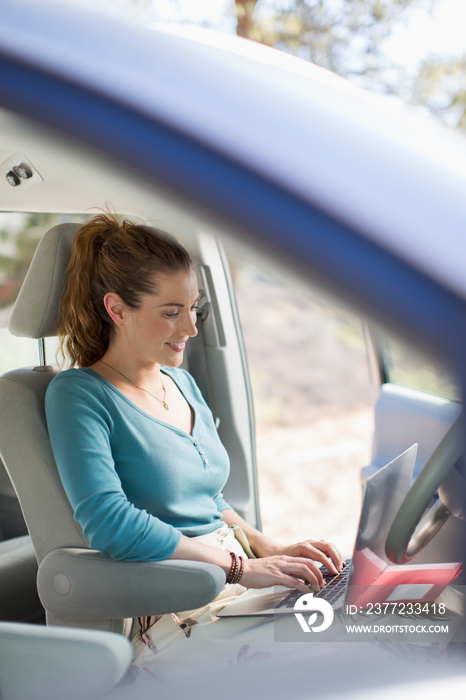 Woman with laptop working inside car