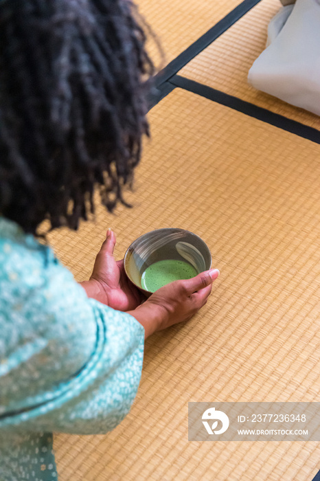 非洲裔美国女性客人将茶碗中的抹茶递给日本女性，茶桅杆