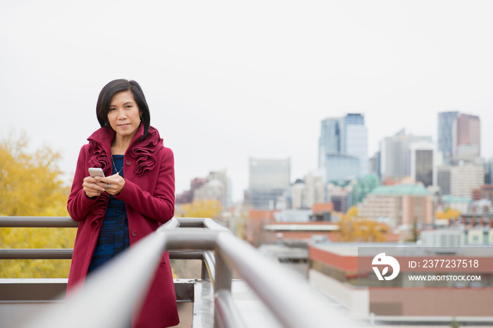 Middle-aged Asian woman using cell phone on rooftop