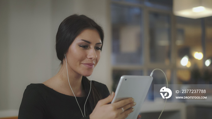 A woman in the office talking with a tablet and smiles. UHD