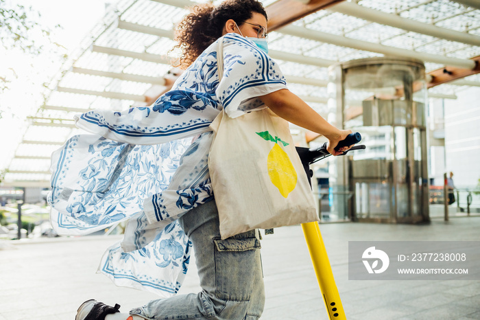 Young woman riding electric scooter on street