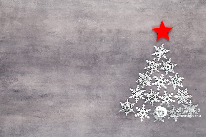 Christmas tree made from white snow flake decoration on gray background. Flat lay, top view