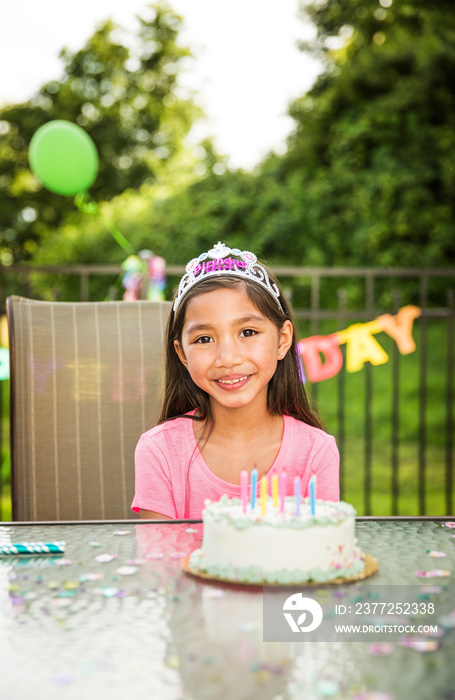 Portrait of smiling girl with cake sitting at table