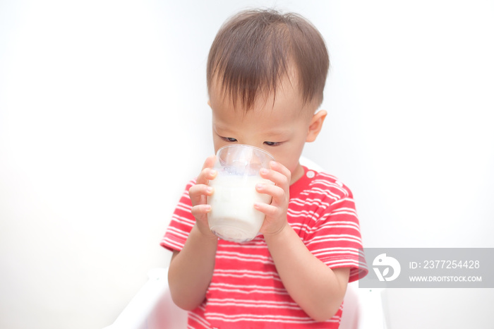 可爱的亚洲人2岁蹒跚学步的男婴从杯子里喝牛奶，小孩坐在高处