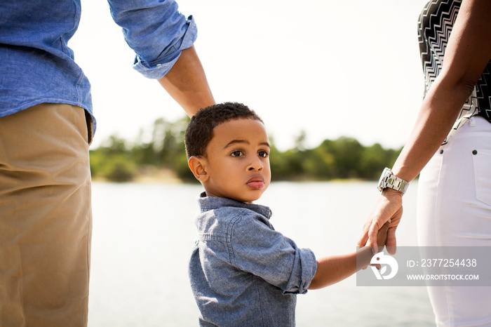 Boy holding hands of his parents outdoors