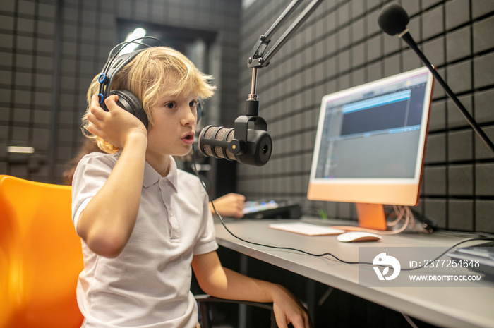 Focused kid broadcasting a program from the radio station