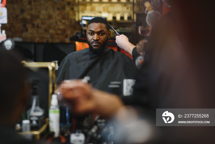 Black man in the barbershop. Cute black man makes a haircut in the African salon. Hair style. Haircu