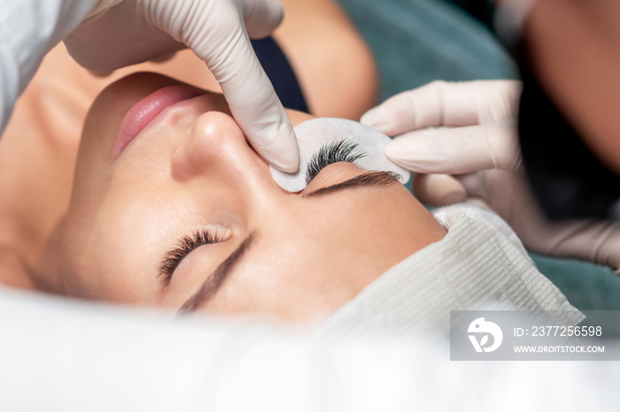 Young woman receiving extending the eyelashes in a beauty salon, close up, eyelash extension procedu