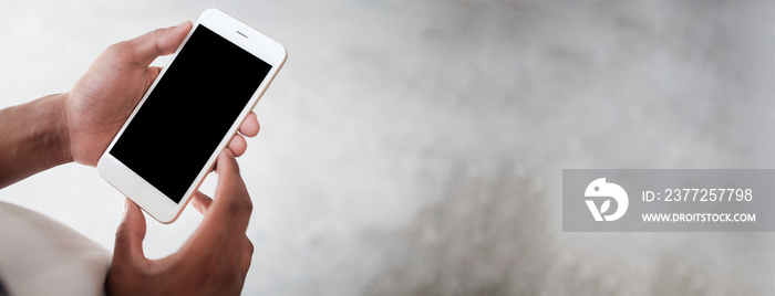 Mock up smartphone of hand holding black mobile phone with blank white screen.