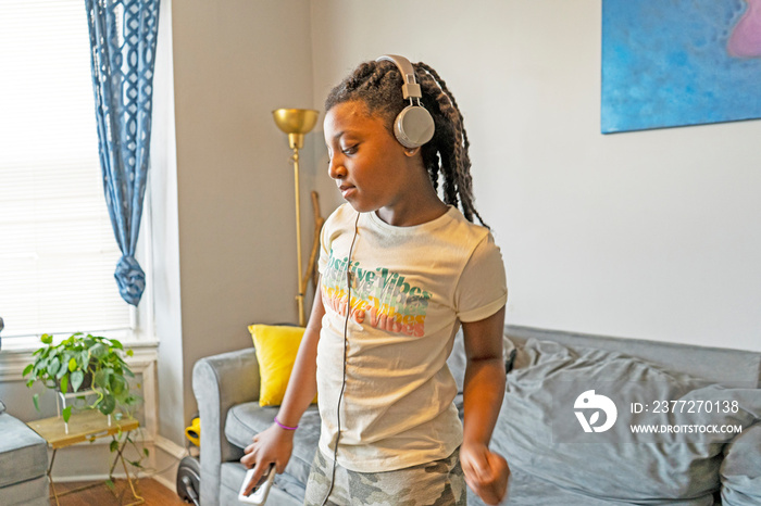 Girl with headphones dancing in living room