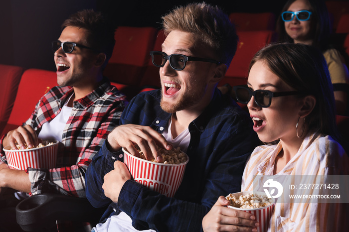 Friends with popcorn watching movie in cinema