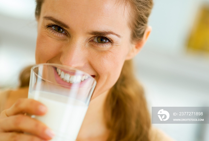 Smiling young woman drinking milk