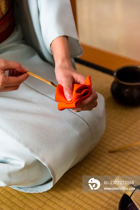 日本女人，茶艺大师，Sen Rikyu，用一块橙色的净化布清洁茶桶