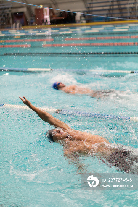 Male swimmers doing backstroke in swimming pool