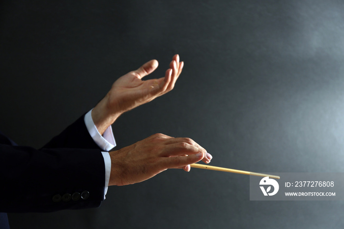 Music conductor hands with baton on black background