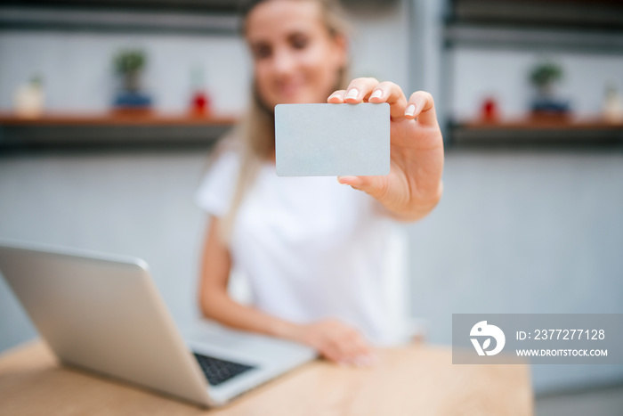 E-commerce concept. Young woman holding a credit card. Focus is on the card.