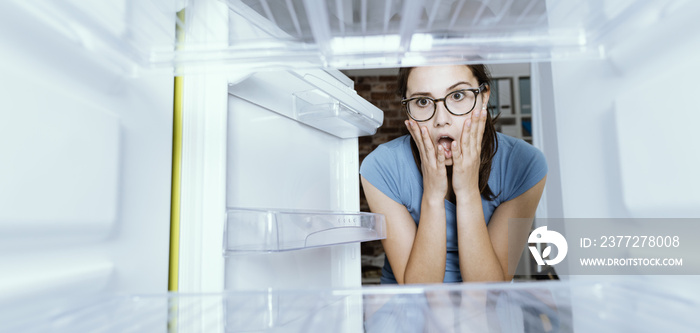 绝望的女人看着她的空冰箱