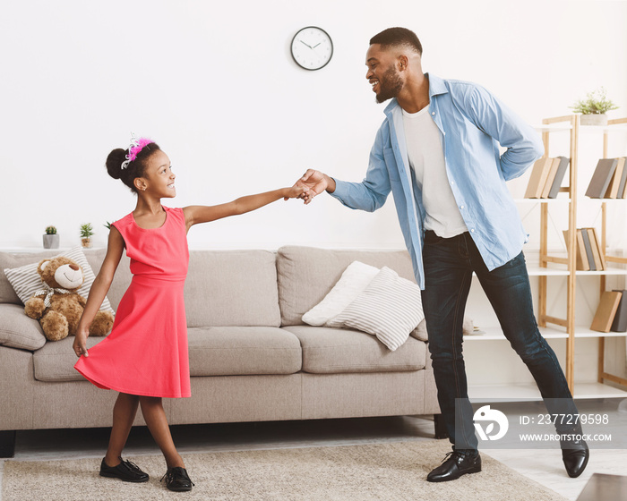 African-american father dancing with daughter at home