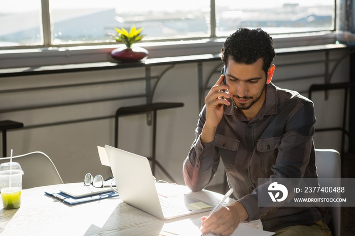 Businessman talking on phone at desk in office