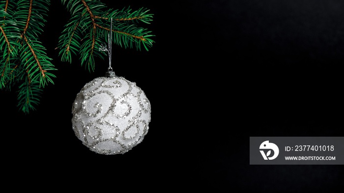 White shiny Christmas ornament decoration hanging on a pine branch