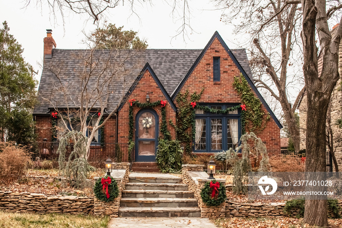 Cute brick cottage with red bows and greenery - decorated for Christmas in bleak wintertime